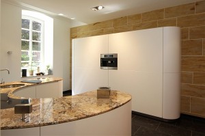 Runde Küche mit Kücheninsel geplant als Halbkreis und mit Granitarbeitsplatte; Schrankwand in Weiß mit Kaffeevollautomat