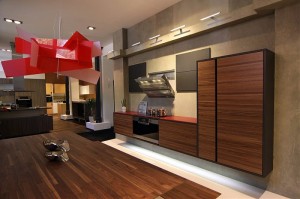 Schwebende Küche, Luxusküche mit horizontal gemaserten Walnuss-Fronten und roter Glasarbeitsplatte
